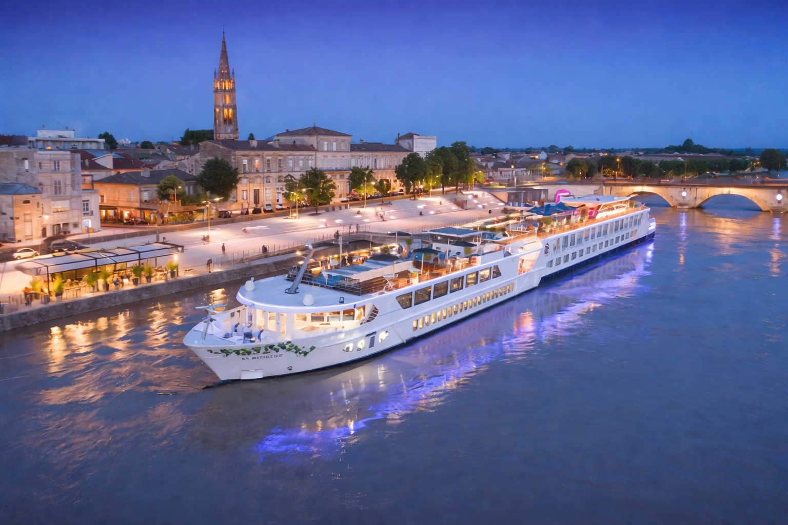 Luxury river cruise ship in Bordeaux on the Garonne River at sunset with illuminated city skyline