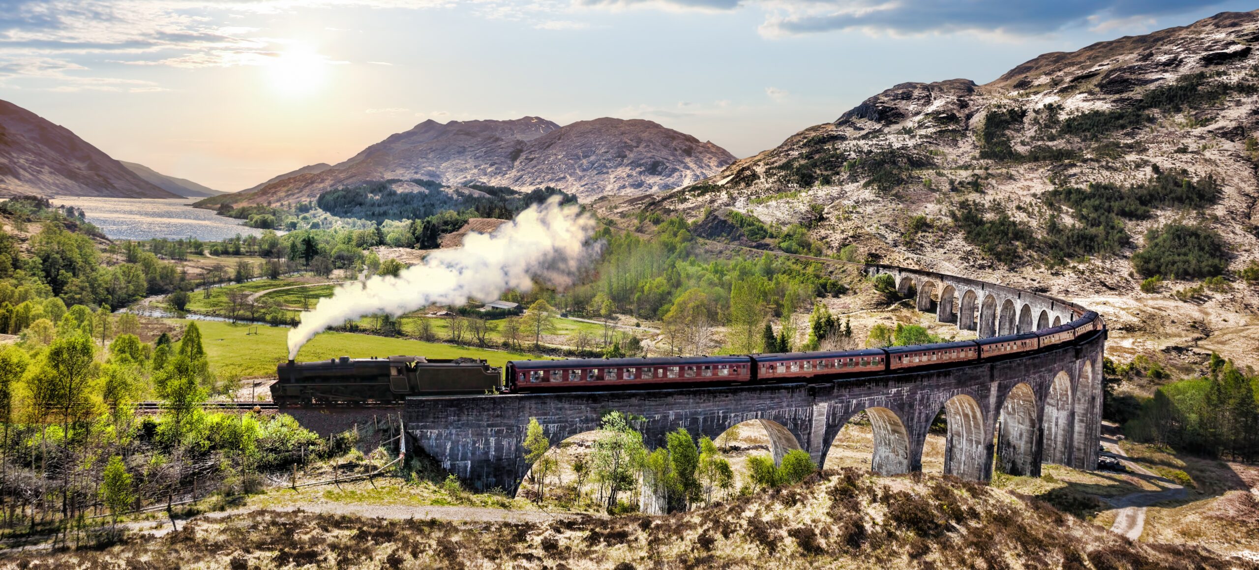 Jacobite steam train crossing the Glenfinnan Viaduct in the Scottish Highlands at sunset