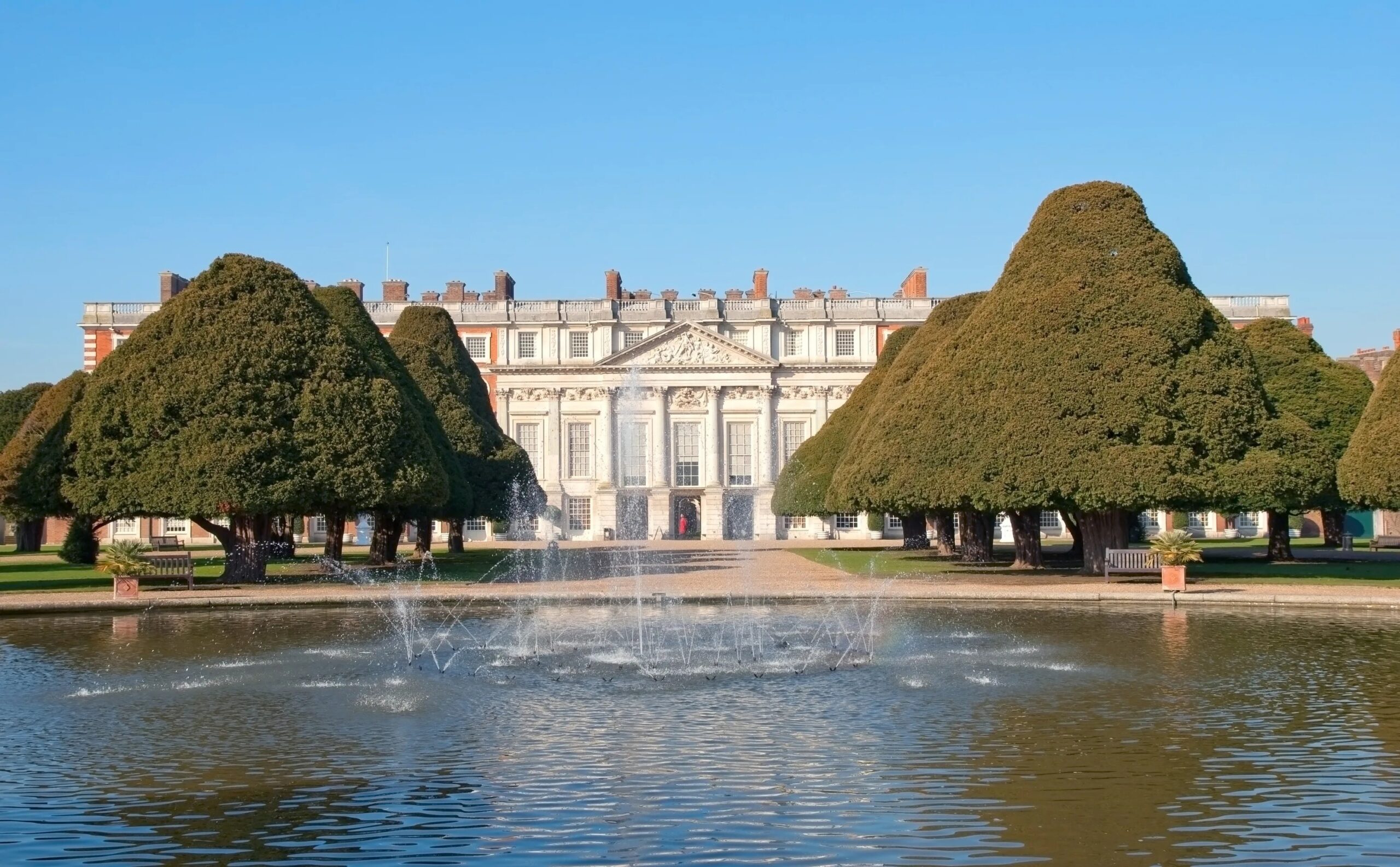 Hampton Court Palace gardens with fountain and Tudor palace façade in London beside the River Thames