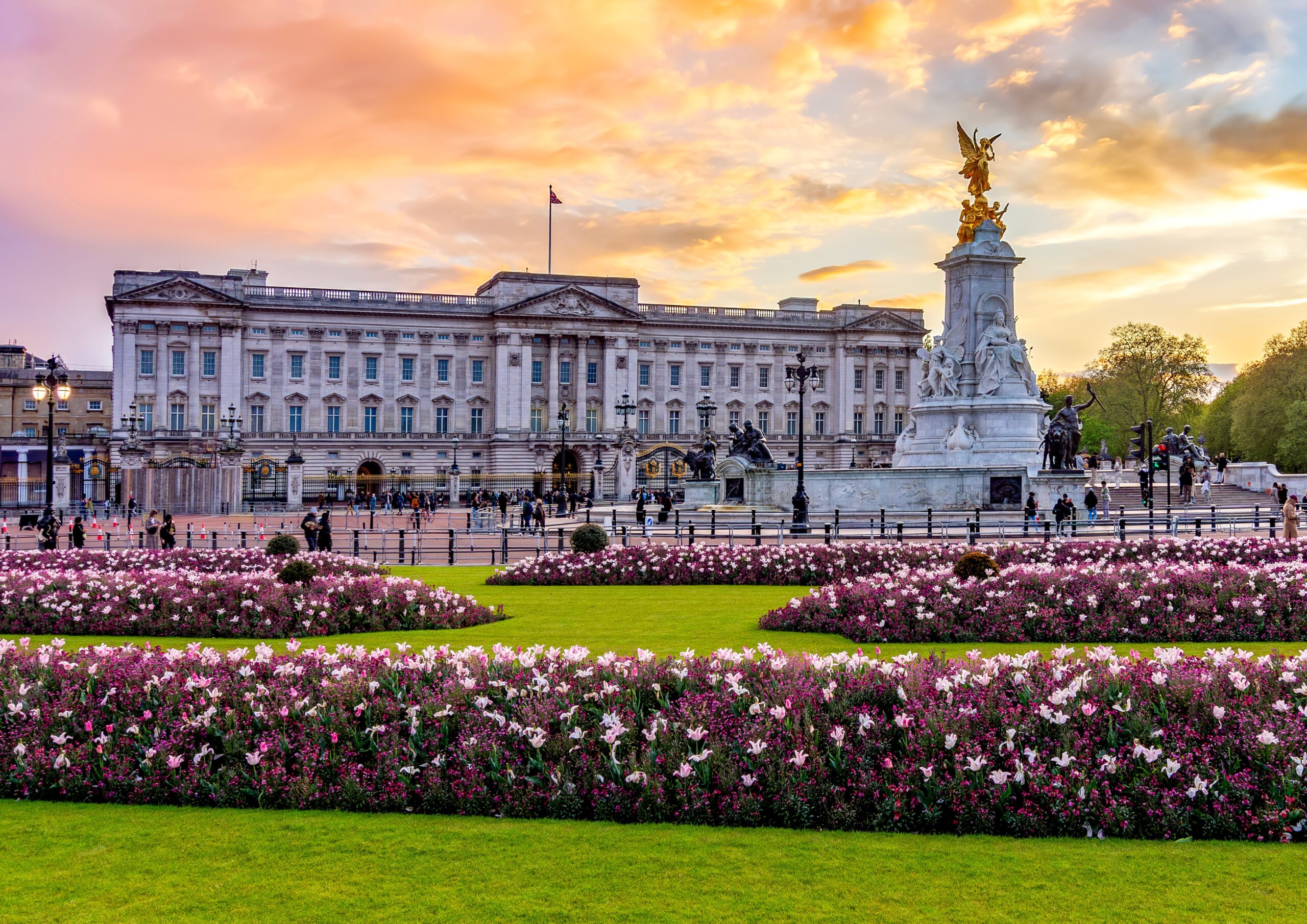 Buckingham Palace and Victoria Memorial at sunset with flower gardens in London